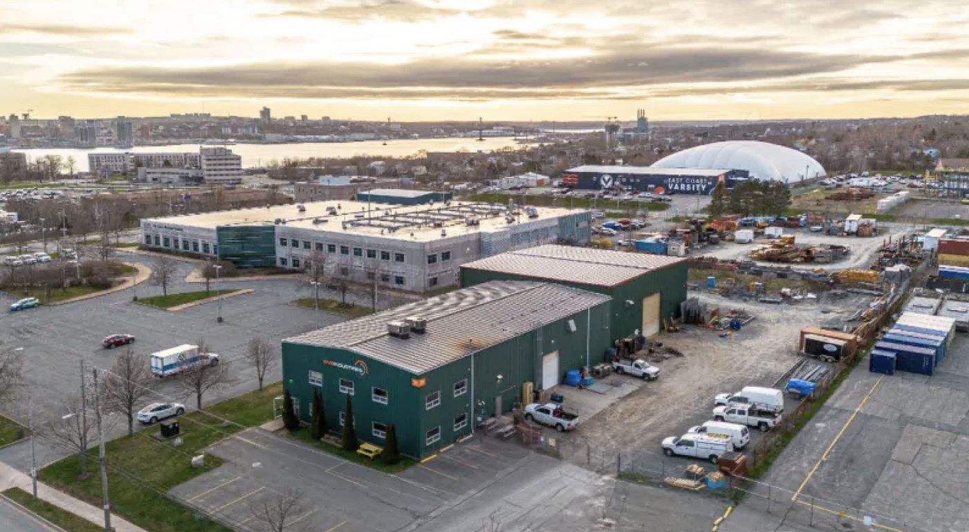 Aerial view of the green commercial building at 31 Mount Hope Avenue in Dartmouth, with Halifax harbour behind it at sunset.